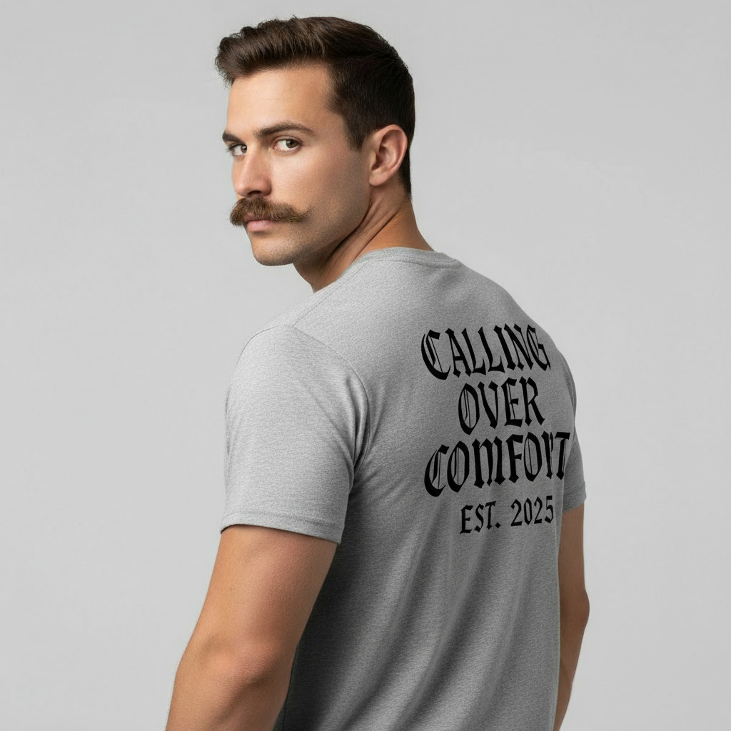 Fit model with mustache showing back of Calling Over Comfort t-shirt